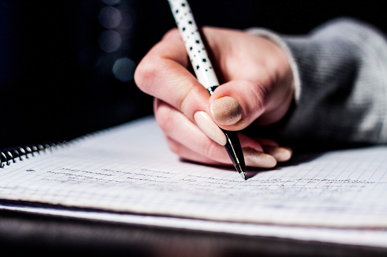 Mão escrevendo anotações em um caderno